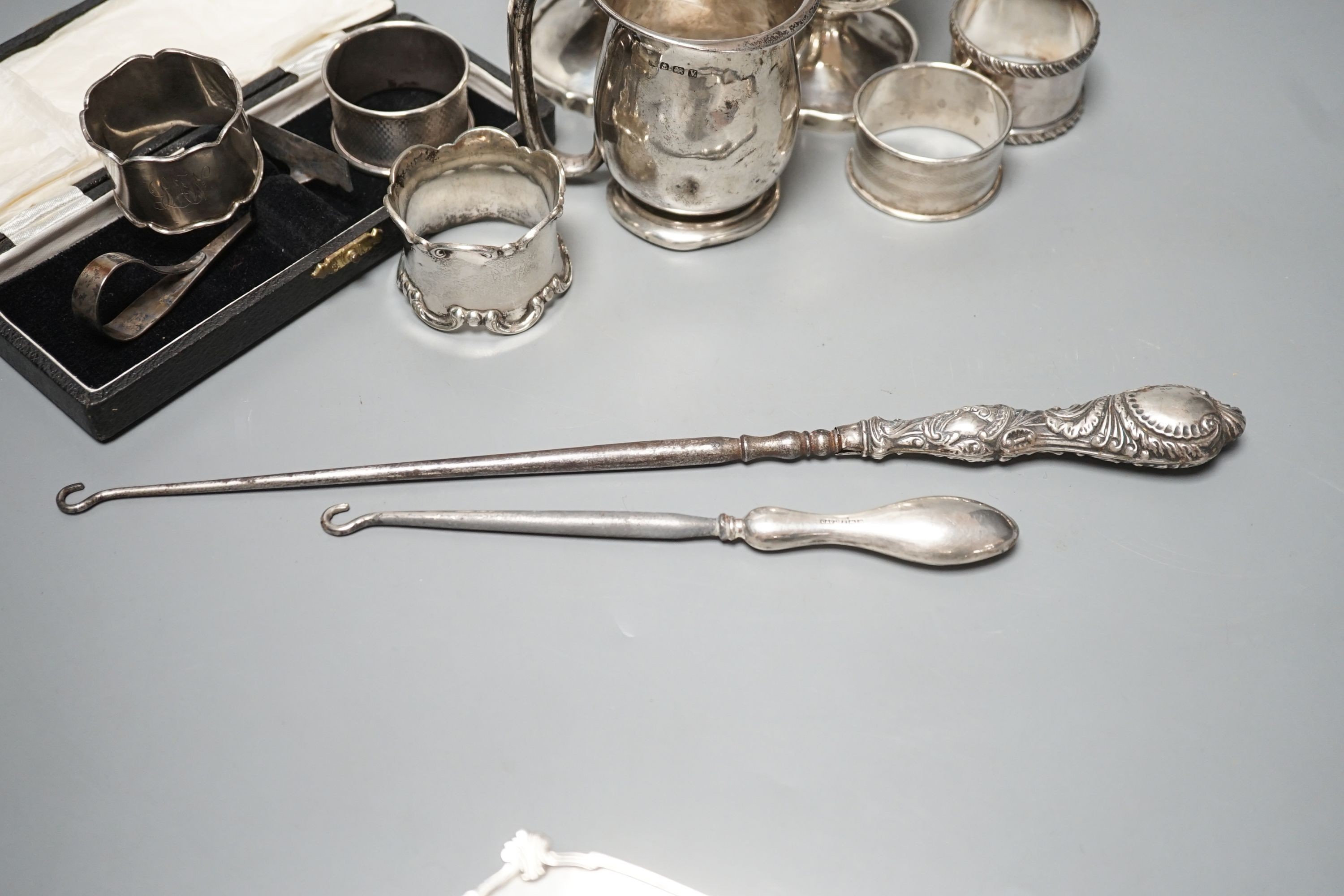 A pair of silver posy vases, a silver mug, a silver dish, five silver napkin rings, two button hooks and a cased silver pusher, weighable silver 9.5oz.